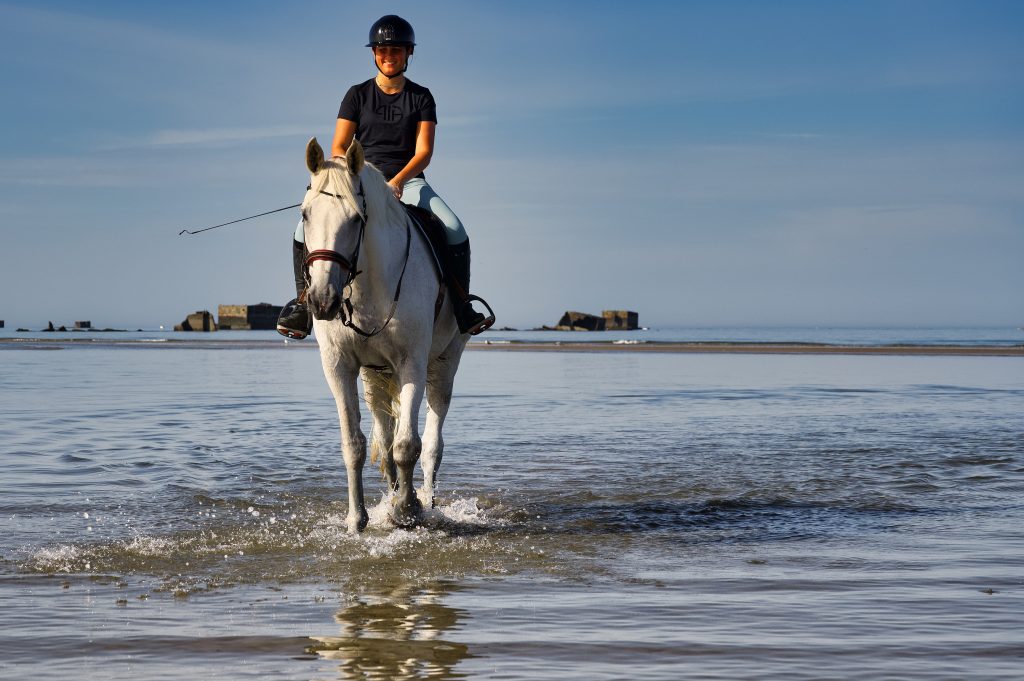 junge Reiterin mit ihrem Pferd am Strand von Saint-Cômes-de-Fresné in der Normandie